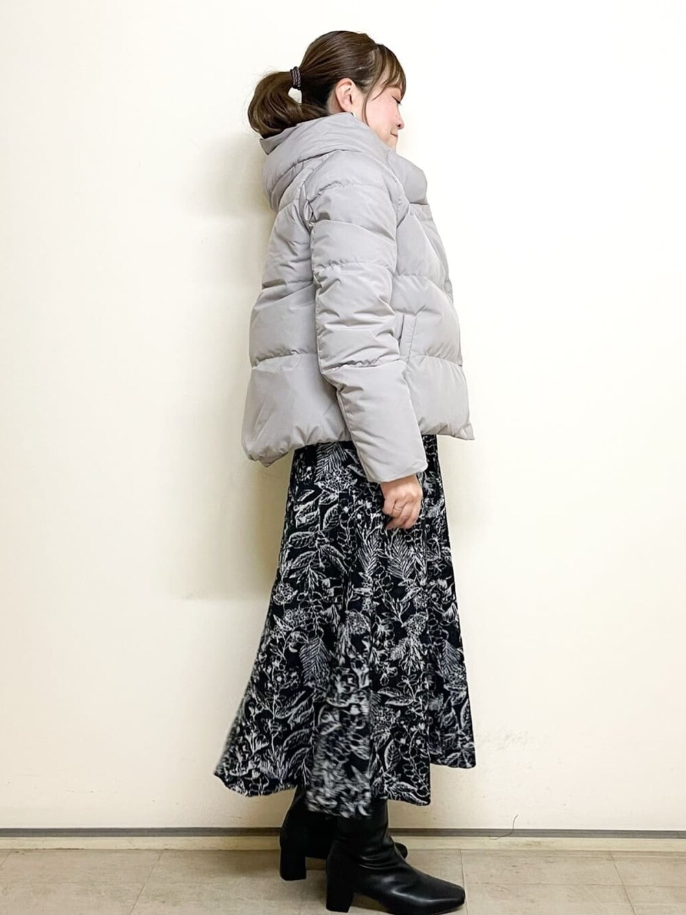 ブラウン系のニット/セーター、グレー系のダウンジャケット/コート、ブラック系のスカートを着用したレディースの冬コーディネートの2枚目の写真