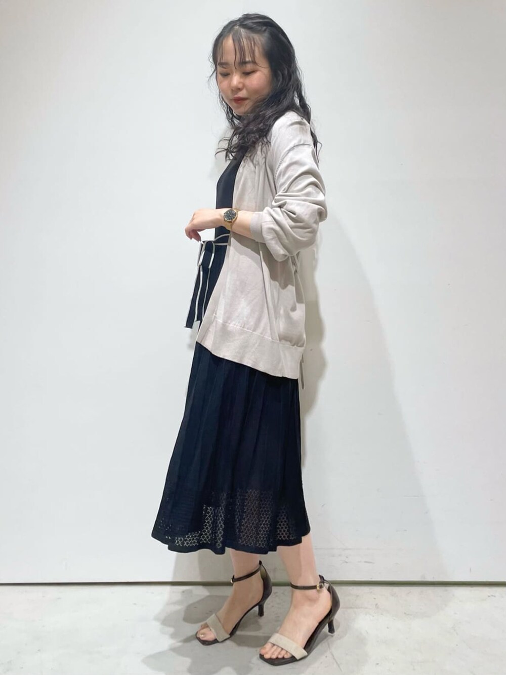 ブラック系のワンピース、グレー系のカーディガン/ボレロ、ベージュ系のサンダルを着用したレディースの春コーディネートの2枚目の写真