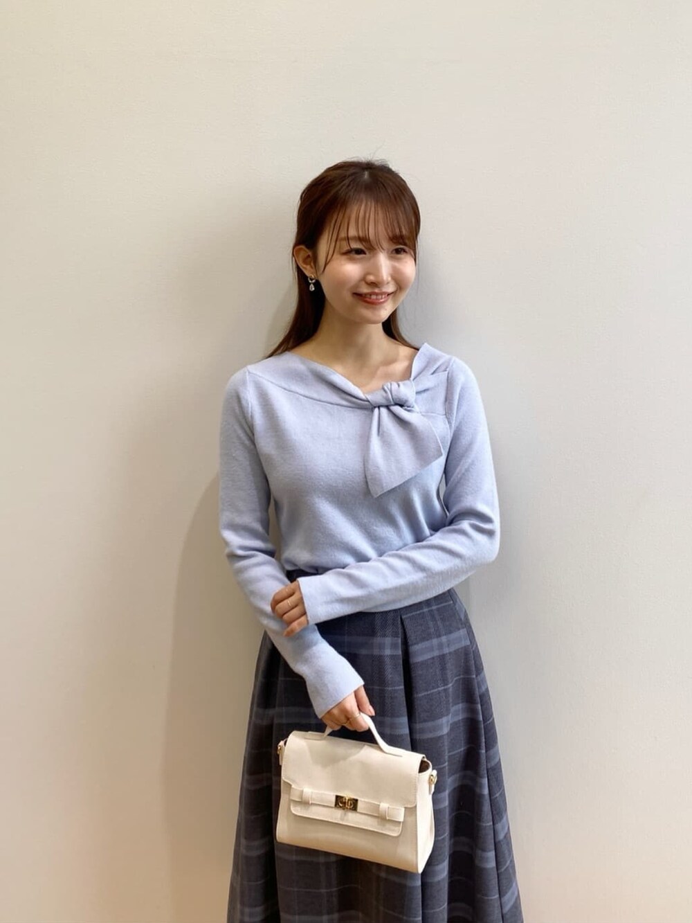 ブルー系のニット/セーター、グレー系のスカート、ホワイト系のショルダーバッグを着用したレディースの秋コーディネートの6枚目の写真