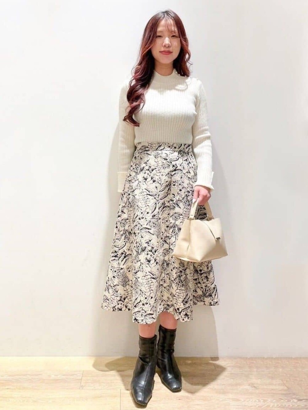 ベージュ系のスカート、ベージュ系のショルダーバッグ、ホワイト系のニット/セーターを着用したレディースの冬コーディネートの4枚目の写真