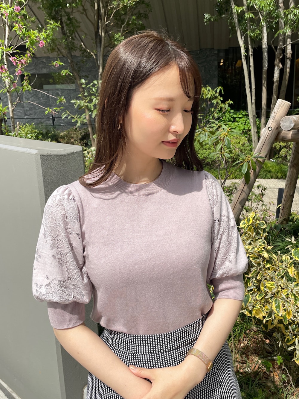 グレー系のニット/セーター、ブラック系のスカート、ベージュ系のショルダーバッグを着用したレディースの春コーディネートの2枚目の写真