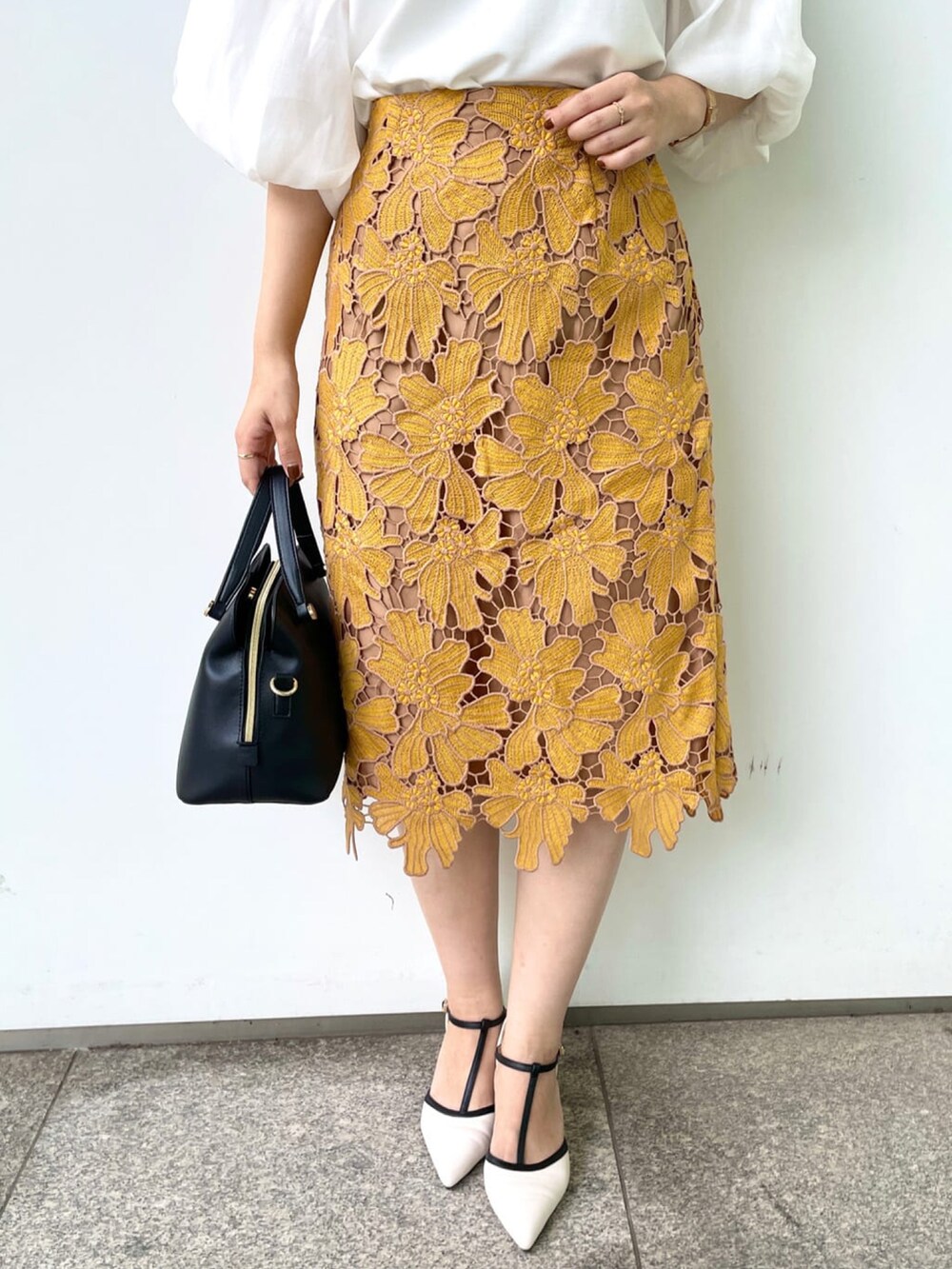 イエロー系のスカート、ホワイト系のTシャツ/カットソー、ブラック系のハンドバッグを着用したレディースの秋コーディネートの5枚目の写真