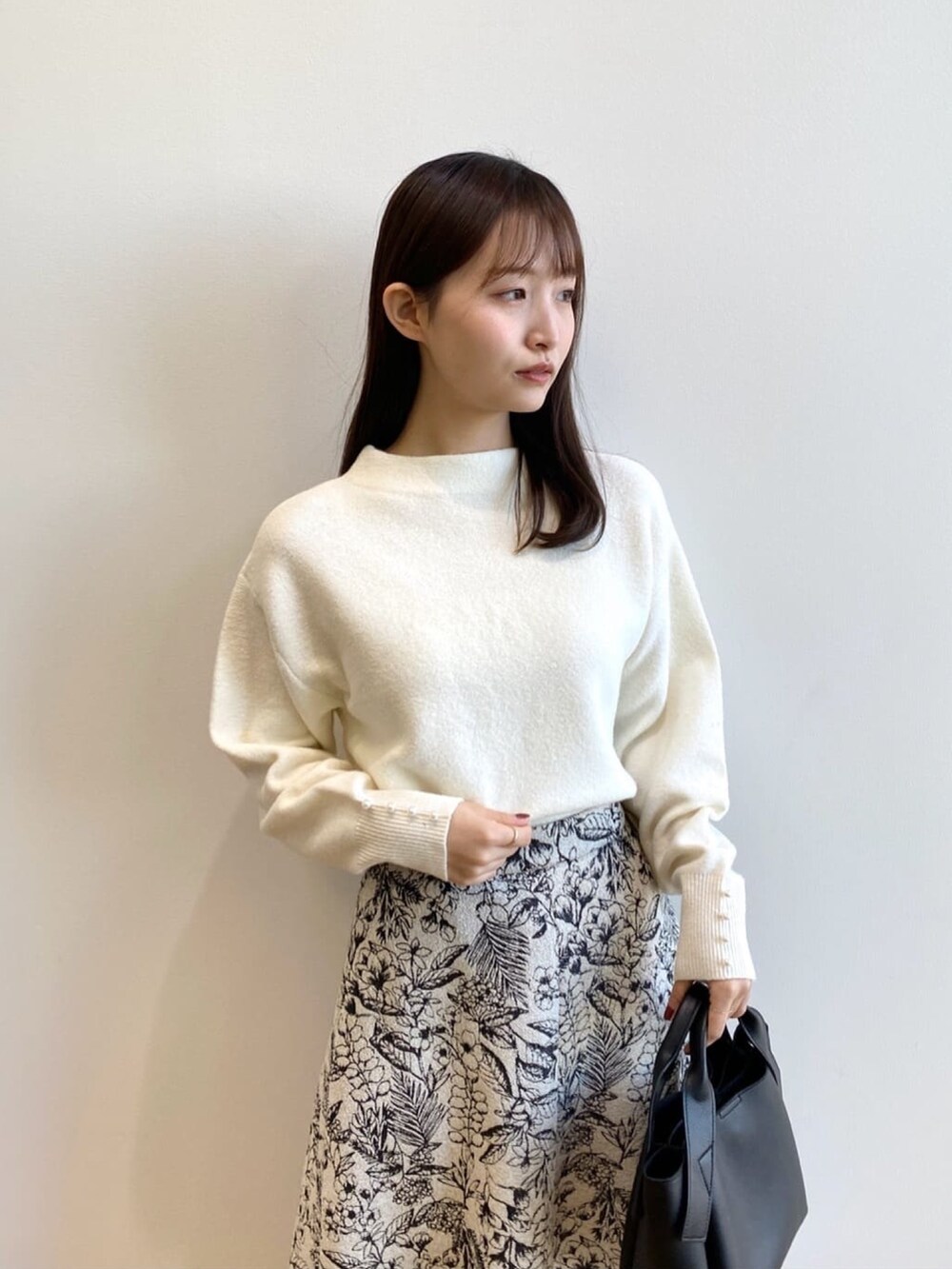 ホワイト系のニット/セーター、ブラック系のショルダーバッグ、ブラック系のブーツを着用したレディースの冬コーディネートの5枚目の写真