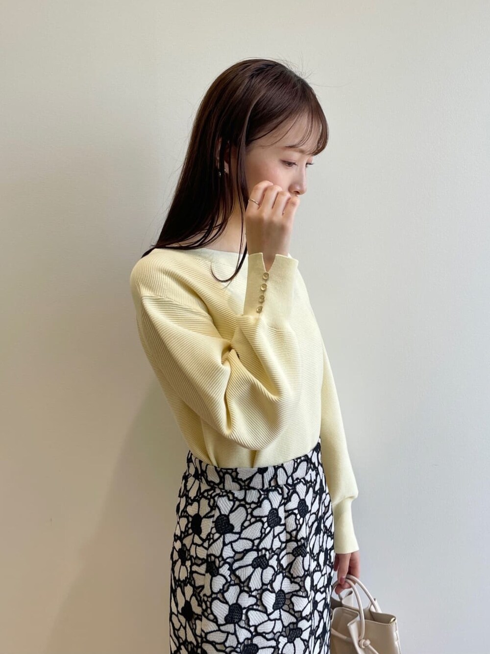 イエロー系のニット/セーター、グレー系のスカート、ホワイト系のショルダーバッグを着用したレディースの春コーディネートの5枚目の写真