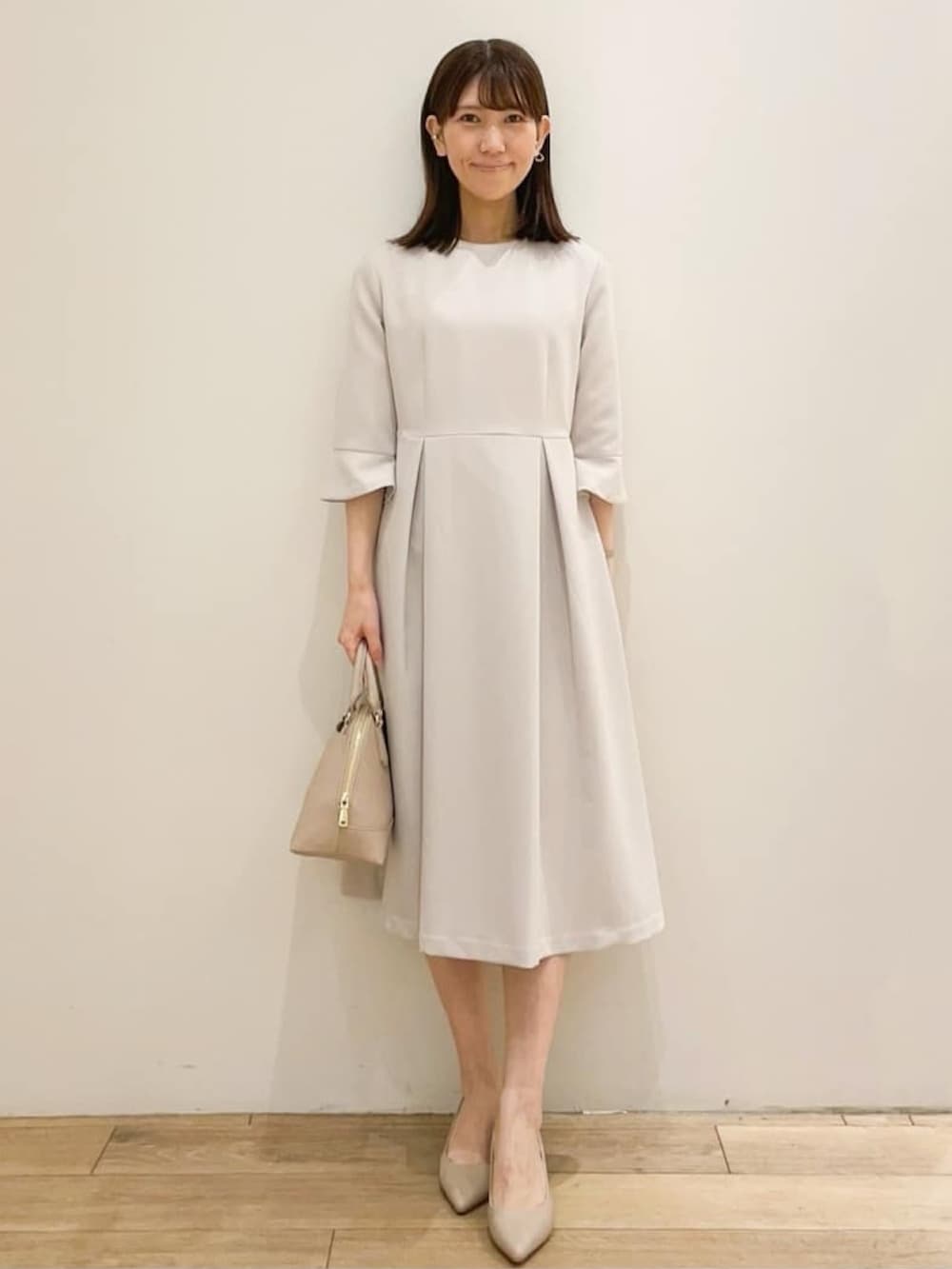 ベージュ系のワンピース、ブラック系のノーカラージャケット、ベージュ系のショルダーバッグを着用したレディースの春コーディネートの2枚目の写真