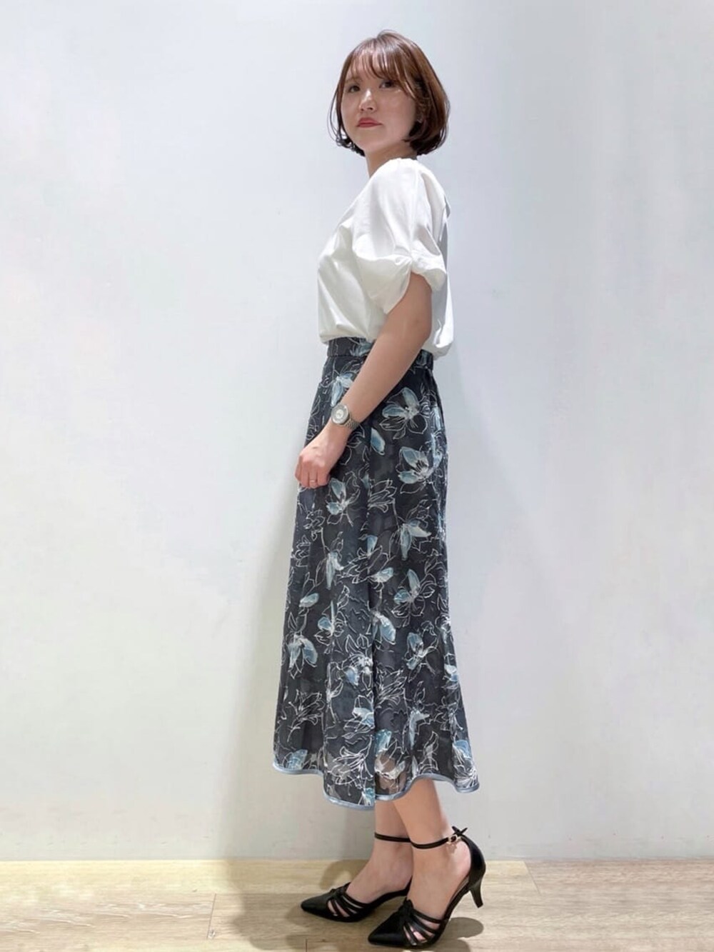 ブラック系のパンプス、グレー系のスカート、ホワイト系のTシャツ/カットソーを着用したレディースの夏コーディネートの2枚目の写真