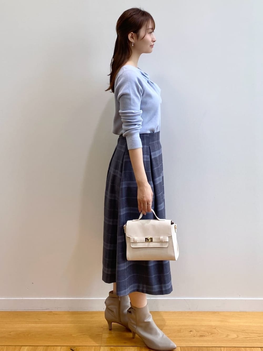 ブルー系のニット/セーター、グレー系のスカート、ホワイト系のショルダーバッグを着用したレディースの秋コーディネートの4枚目の写真