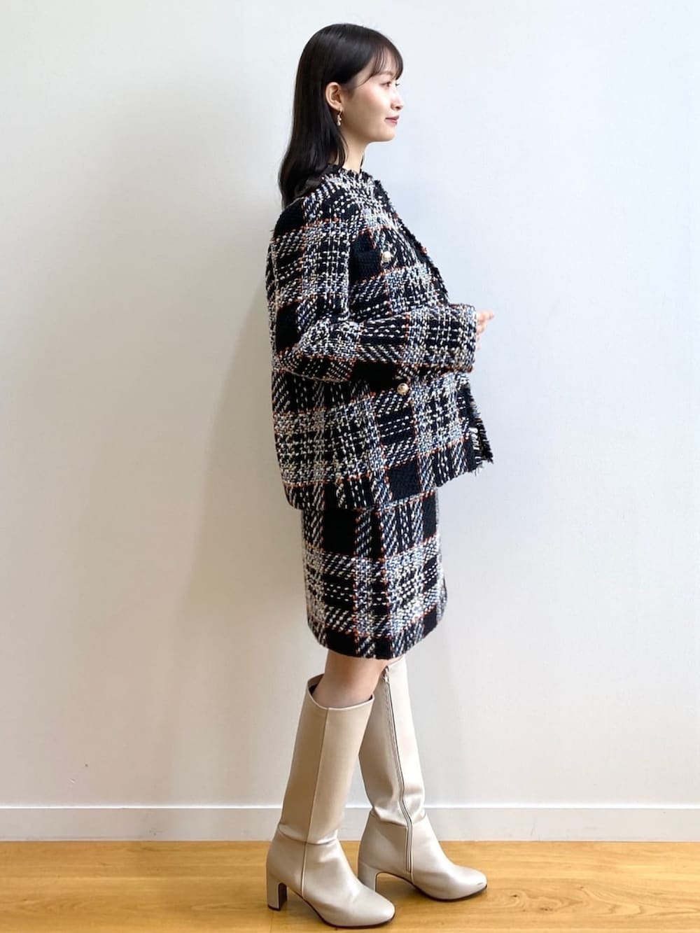 ブラック系のノーカラーコート、ブラック系のスカート、ブラック系のニット/セーターを着用したレディースの冬コーディネートの2枚目の写真