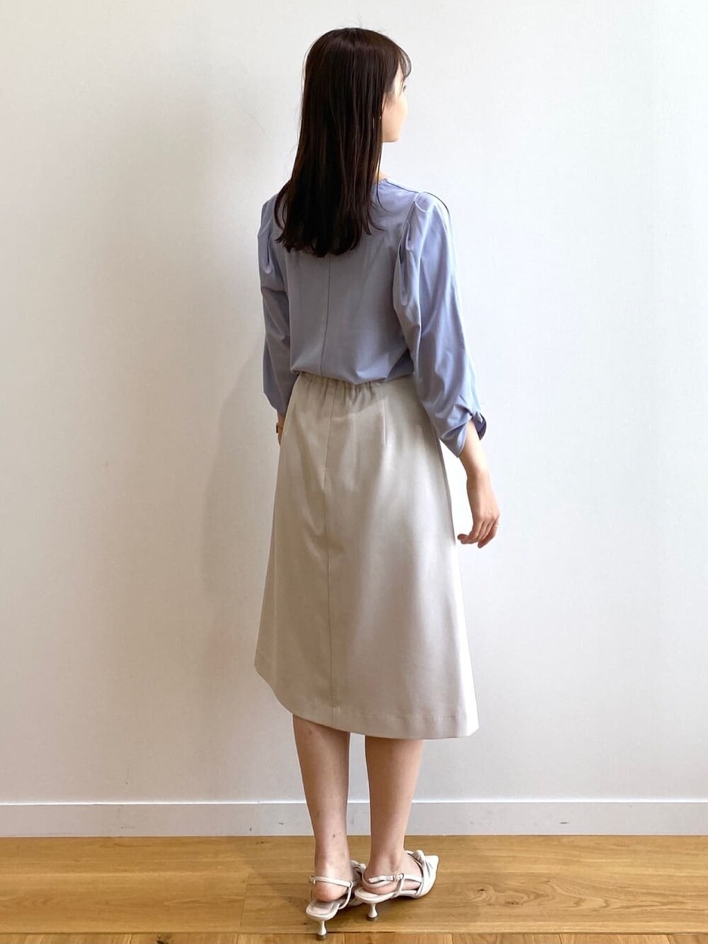 グレー系のスカート、ブルー系のTシャツ/カットソー、ホワイト系のパンプスを着用したレディースの春コーディネートの3枚目の写真