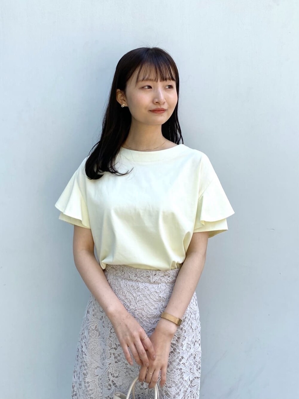 イエロー系のTシャツ/カットソー、ベージュ系のスカート、ホワイト系のショルダーバッグを着用したレディースの春コーディネートの5枚目の写真