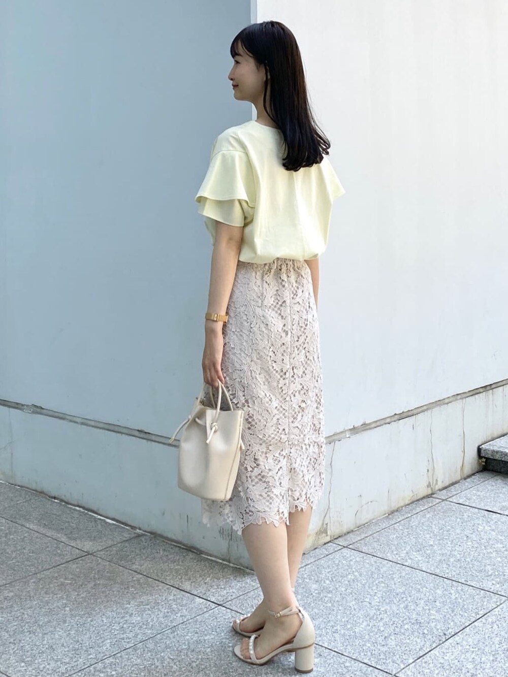 イエロー系のTシャツ/カットソー、ベージュ系のスカート、ホワイト系のショルダーバッグを着用したレディースの春コーディネートの4枚目の写真