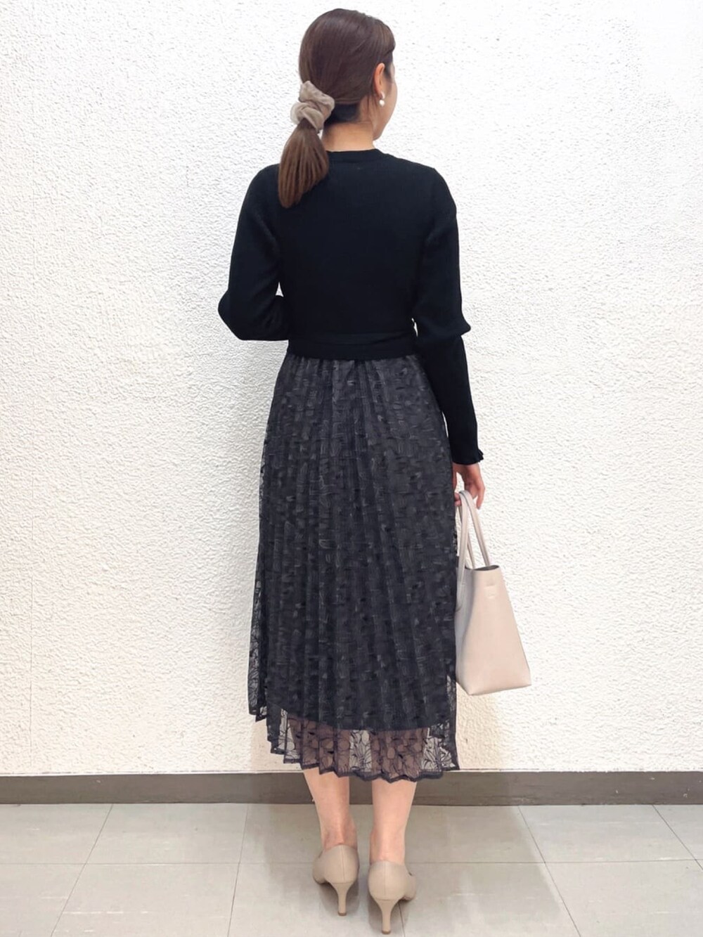 ブラック系のワンピース、ベージュ系のノーカラーコート、ベージュ系のパンプスを着用したレディースの春コーディネートの5枚目の写真