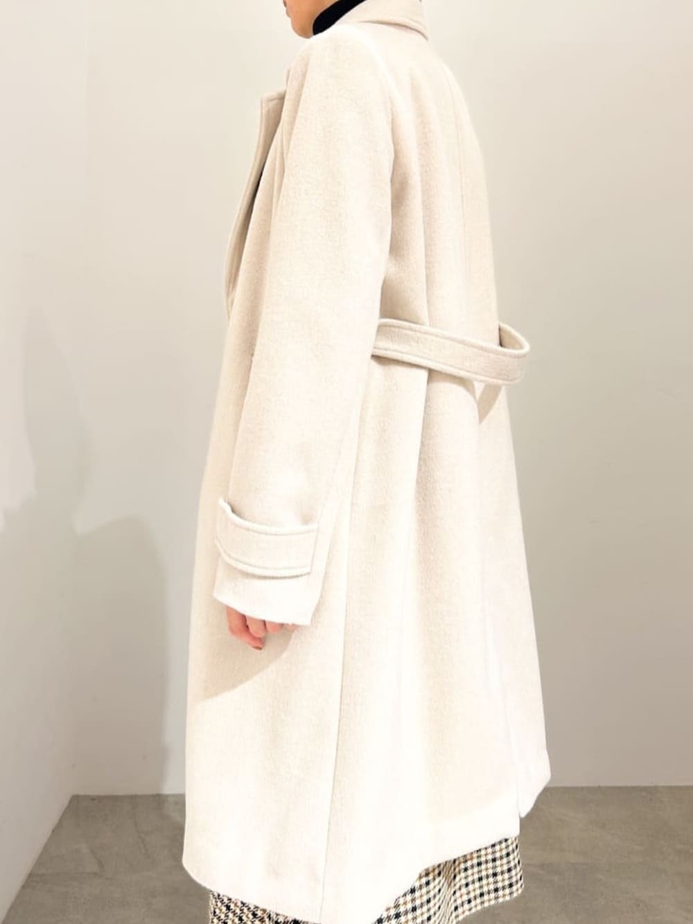 ベージュ系のチェスターコート、ブラック系のニット/セーター、ベージュ系のワンピースを着用したレディースの秋コーディネートの3枚目の写真