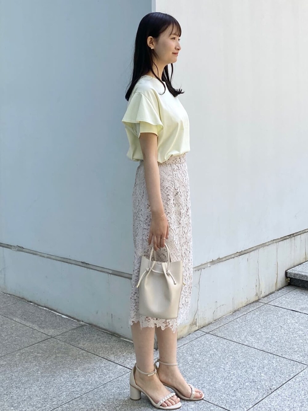 イエロー系のTシャツ/カットソー、ベージュ系のスカート、ホワイト系のショルダーバッグを着用したレディースの春コーディネートの2枚目の写真