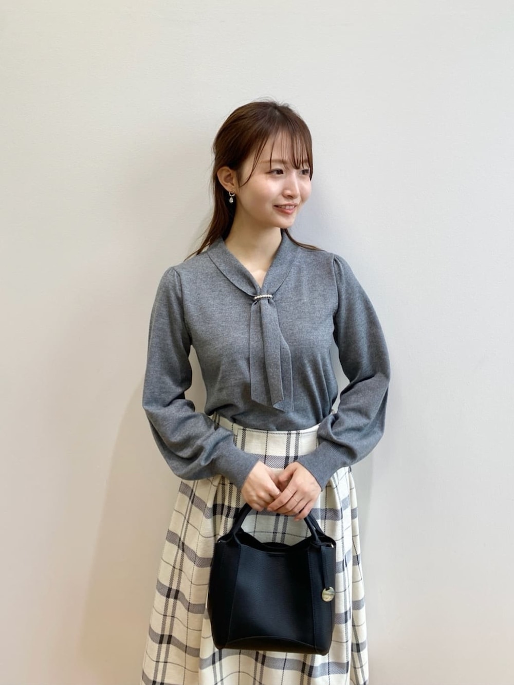 グレー系のニット/セーター、ベージュ系のスカート、ブラック系のブーツを着用したレディースの秋コーディネートの6枚目の写真