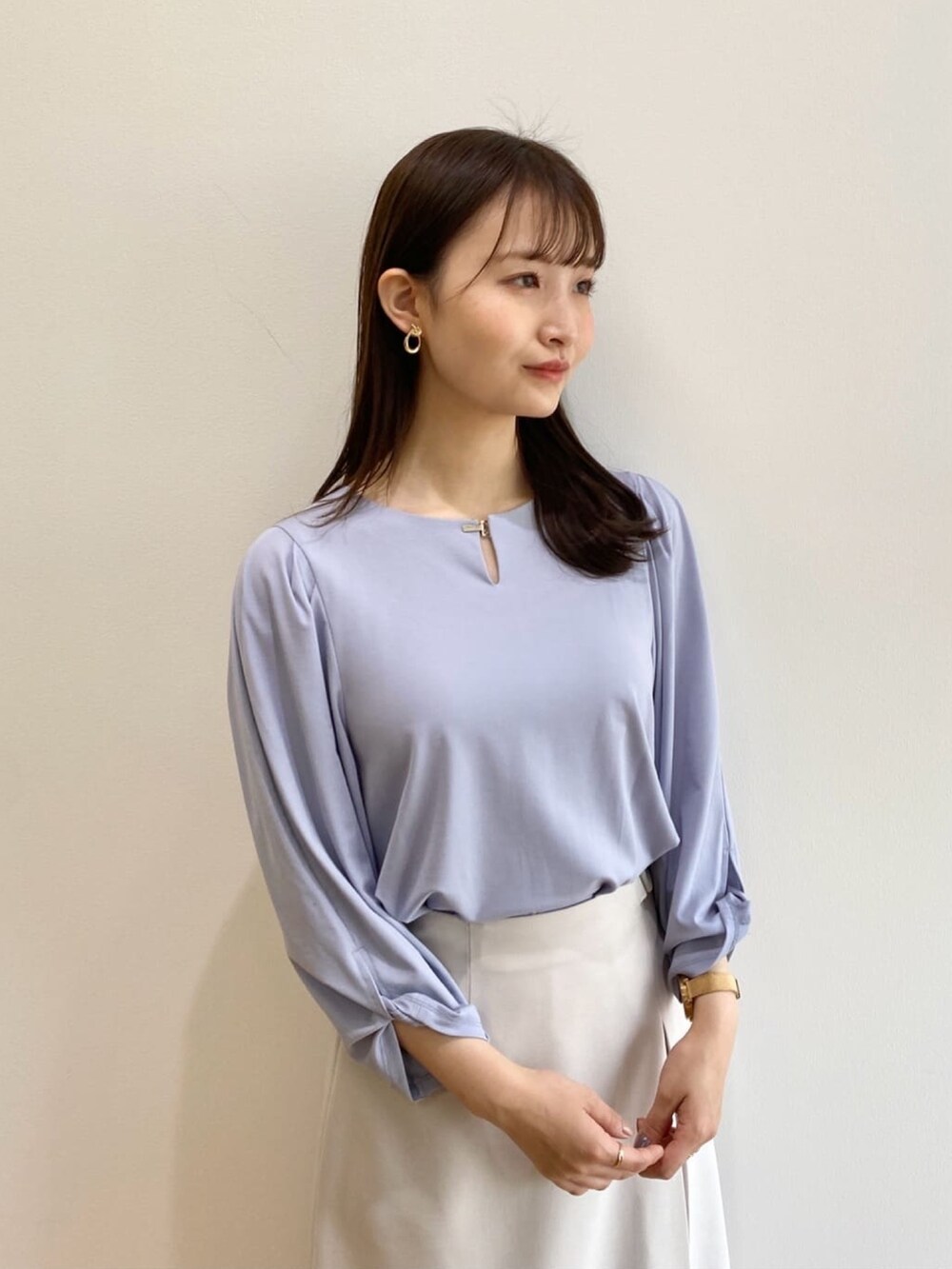 グレー系のスカート、ブルー系のTシャツ/カットソー、ホワイト系のパンプスを着用したレディースの春コーディネートの4枚目の写真