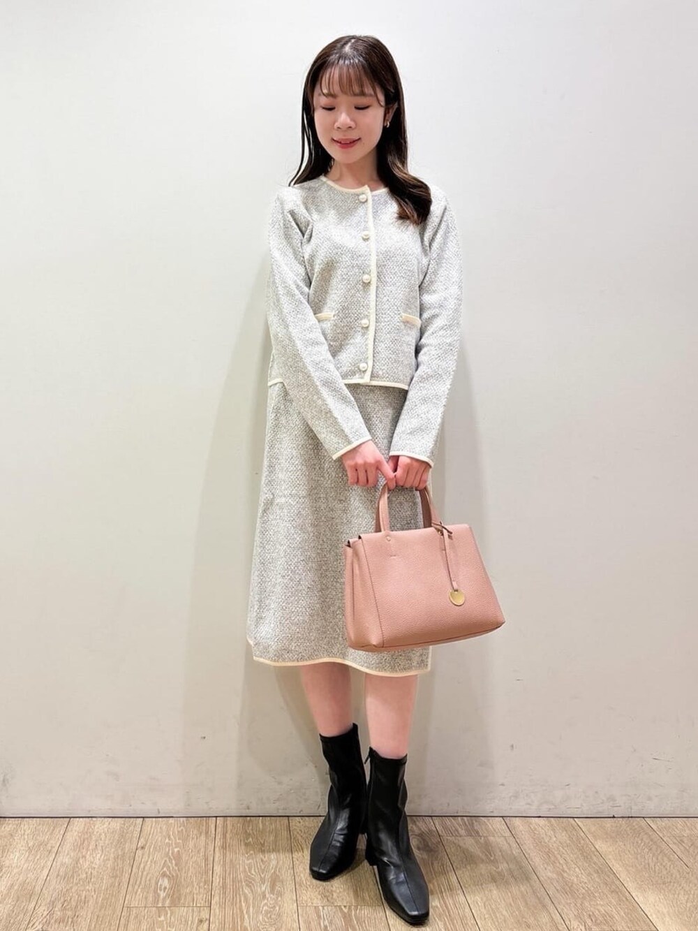 グレー系のカーディガン/ボレロ、グレー系のスカート、ブラック系のブーツを着用したレディースの秋コーディネートの2枚目の写真