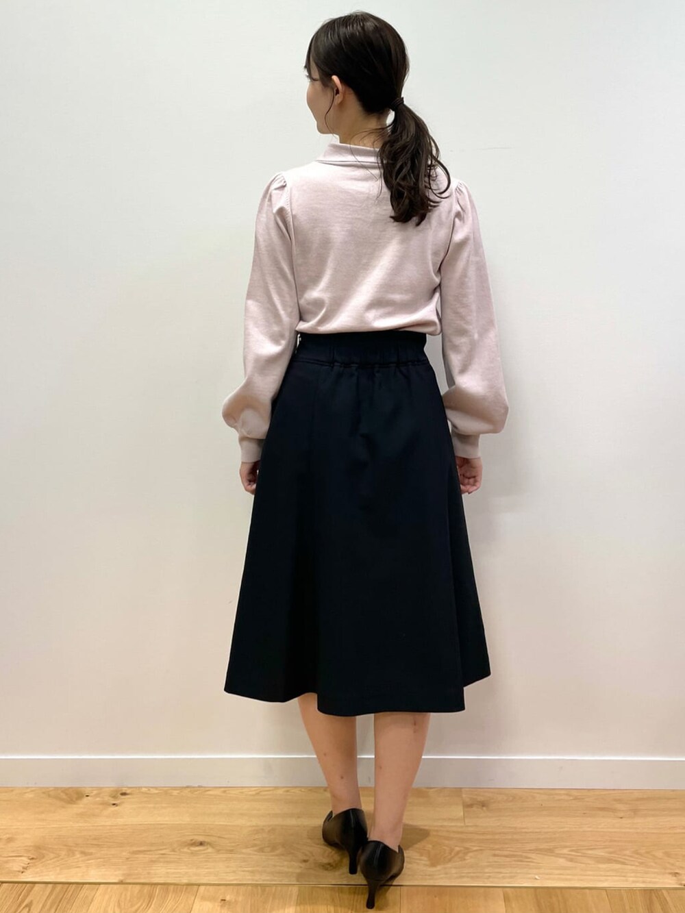 ピンク系のニット/セーター、ブラック系のスカート、ブラック系のパンプスを着用したレディースの秋コーディネートの3枚目の写真