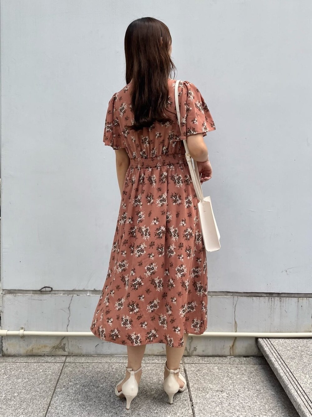 オレンジ系のワンピース、ホワイト系のショルダーバッグ、ホワイト系のパンプスを着用したレディースの夏コーディネートの3枚目の写真