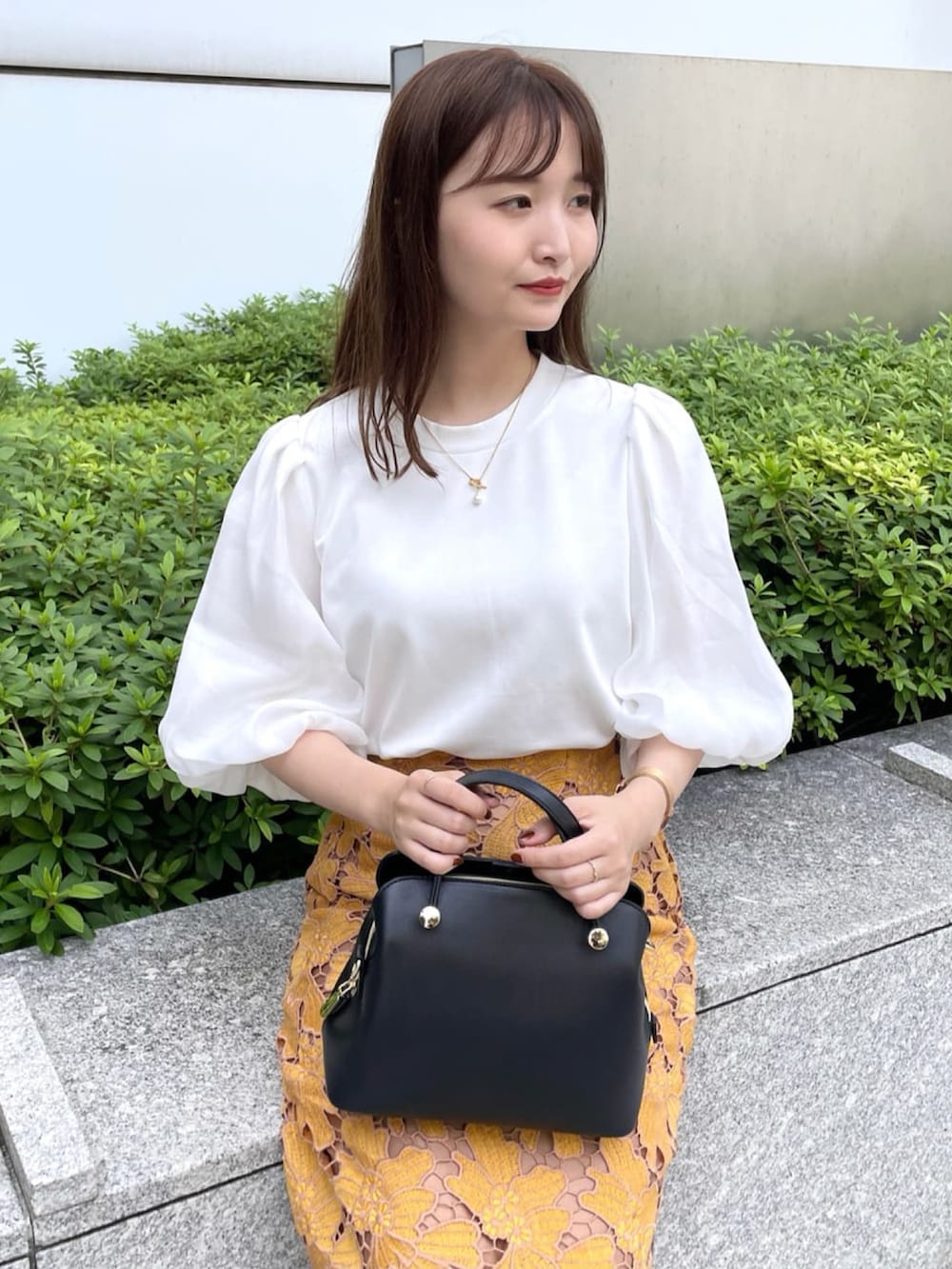 イエロー系のスカート、ホワイト系のTシャツ/カットソー、ブラック系のハンドバッグを着用したレディースの秋コーディネートの4枚目の写真