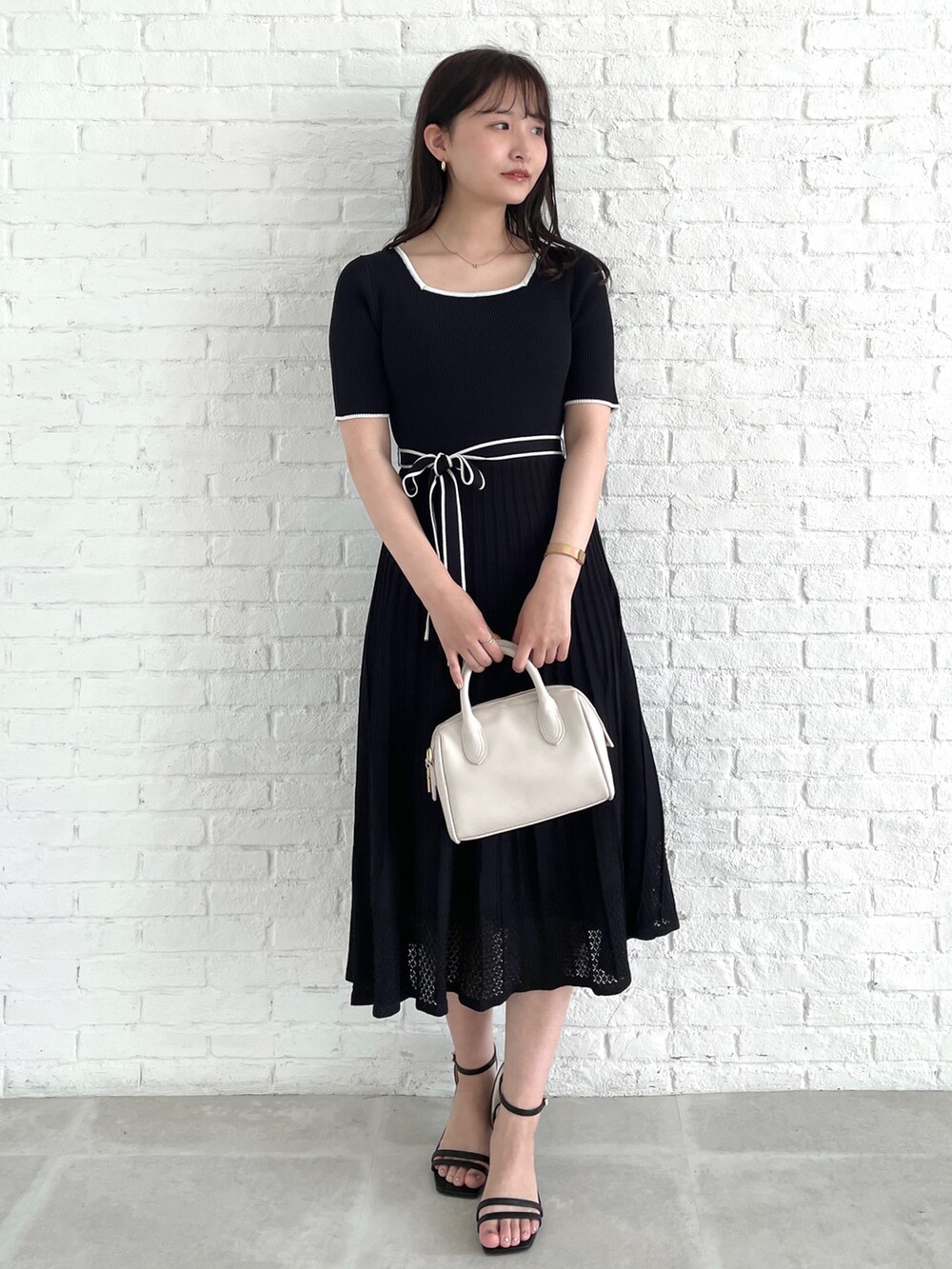 ブラック系のワンピース、ブラック系のカーディガン/ボレロ、グレー系のショルダーバッグを着用したレディースの春コーディネートの2枚目の写真