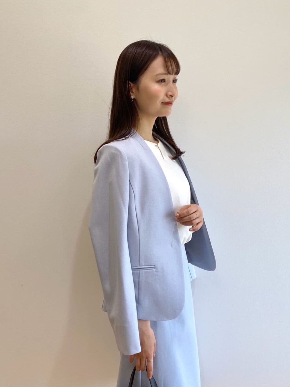 ブルー系のノーカラージャケット、ブルー系のスカート、ブラック系のハンドバッグを着用したレディースの春コーディネートの5枚目の写真