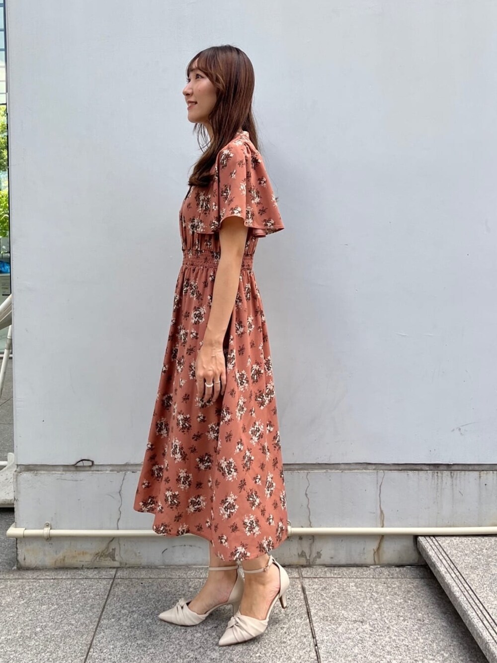 オレンジ系のワンピース、ホワイト系のショルダーバッグ、ホワイト系のパンプスを着用したレディースの夏コーディネートの2枚目の写真