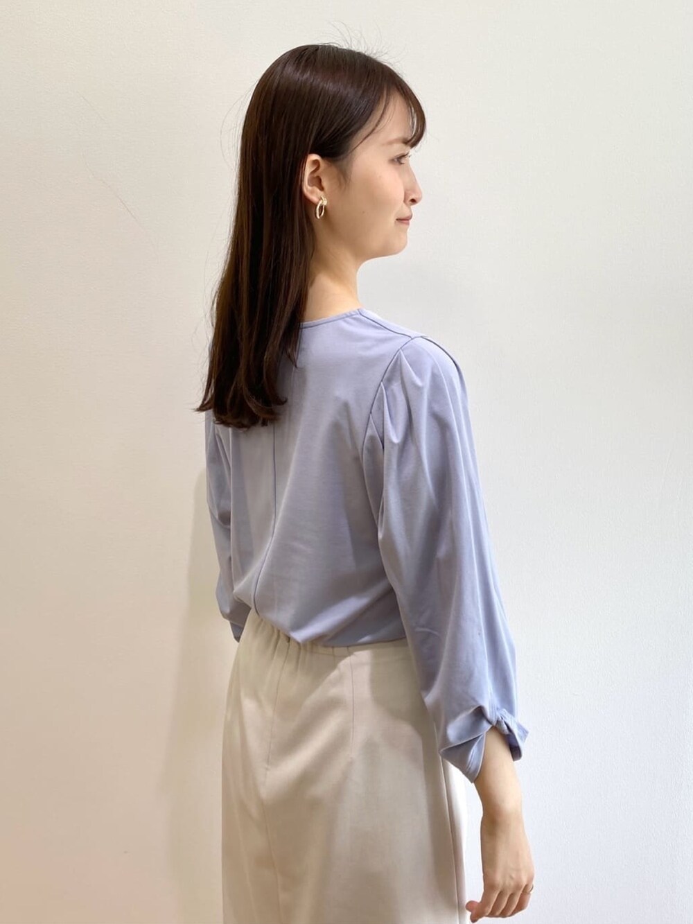 グレー系のスカート、ブルー系のTシャツ/カットソー、ホワイト系のパンプスを着用したレディースの春コーディネートの6枚目の写真