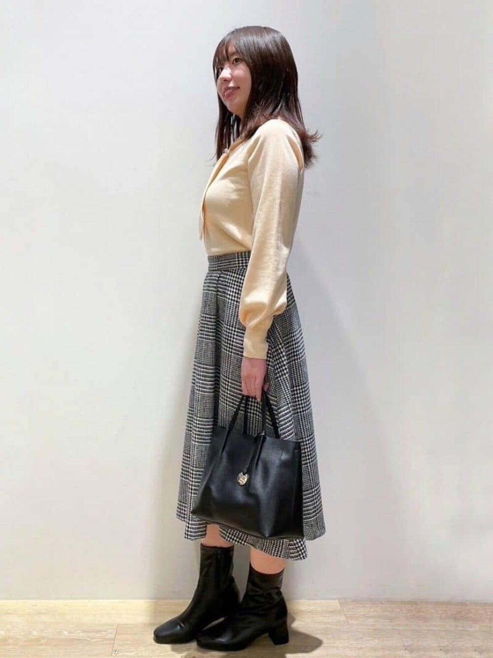 ブラック系のスカート、オレンジ系のニット/セーター、ブラック系のトートバッグを着用したレディースの冬コーディネートの2枚目の写真