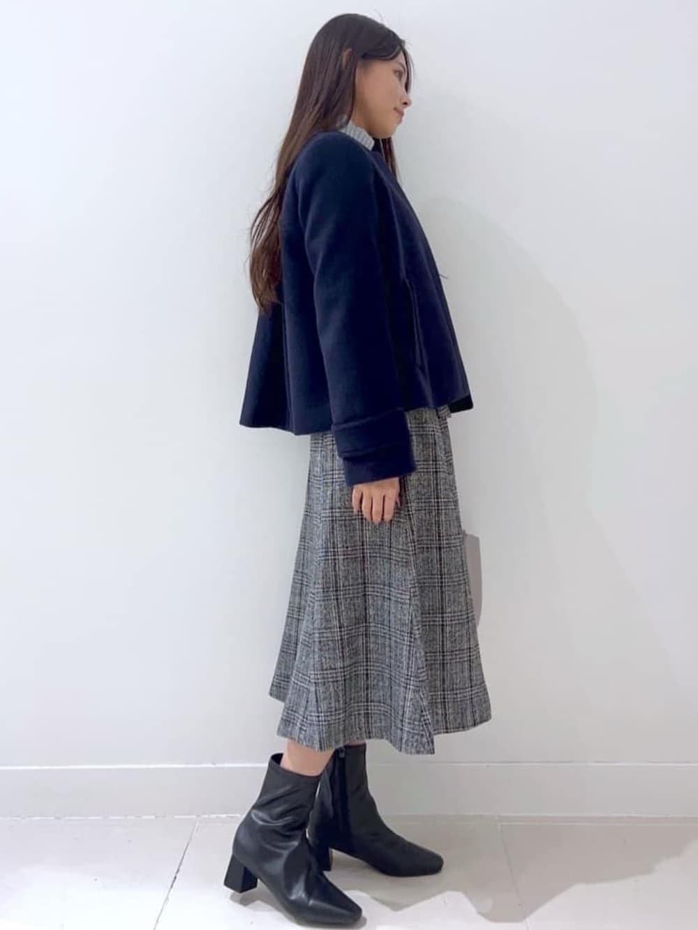 ブルー系のノーカラーコート、グレー系のニット/セーター、ブラック系のブーツを着用したレディースの秋コーディネートの2枚目の写真