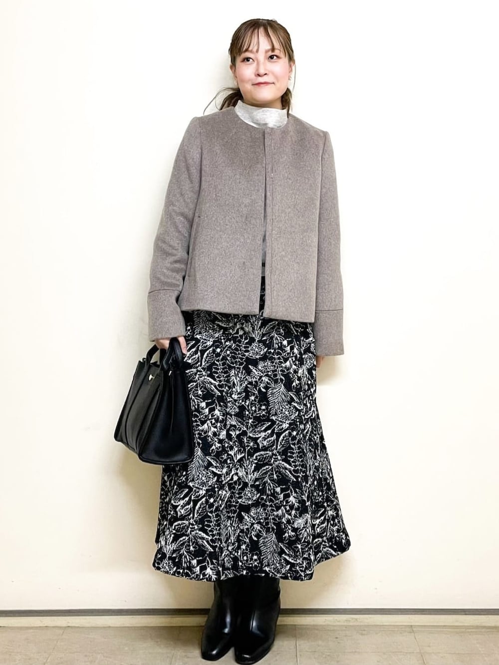 ベージュ系のニット/セーター、ブラック系のスカート、ブラック系のトートバッグを着用したレディースの冬コーディネートの2枚目の写真