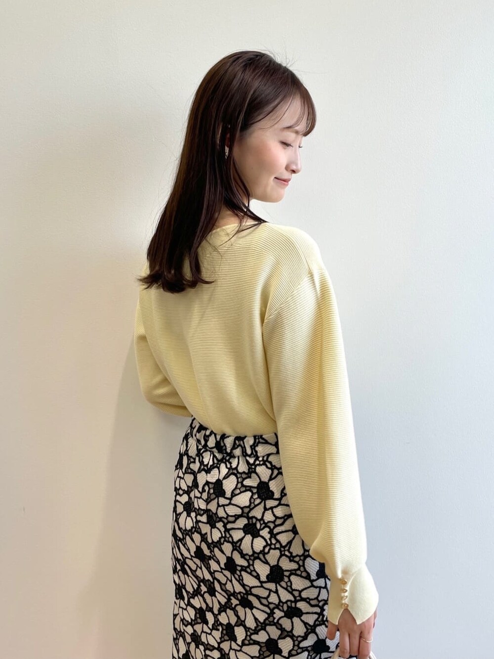 イエロー系のニット/セーター、グレー系のスカート、ホワイト系のショルダーバッグを着用したレディースの春コーディネートの6枚目の写真