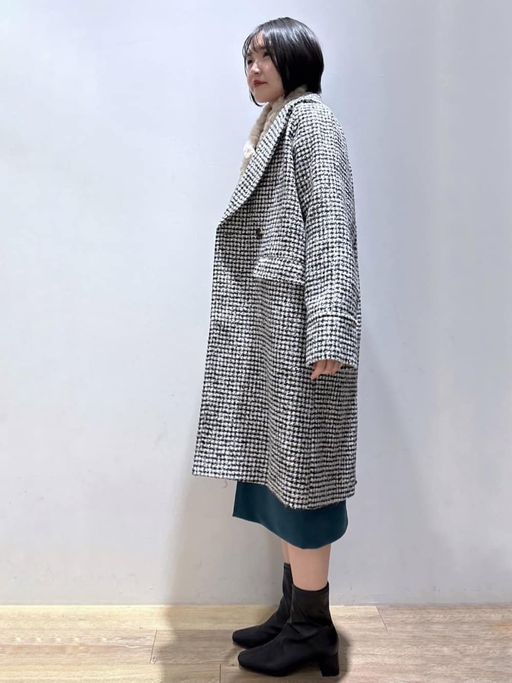 ベージュ系のニット/セーター、ブラック系のチェスターコート、ブルー系のスカートを着用したレディースの冬コーディネートの3枚目の写真