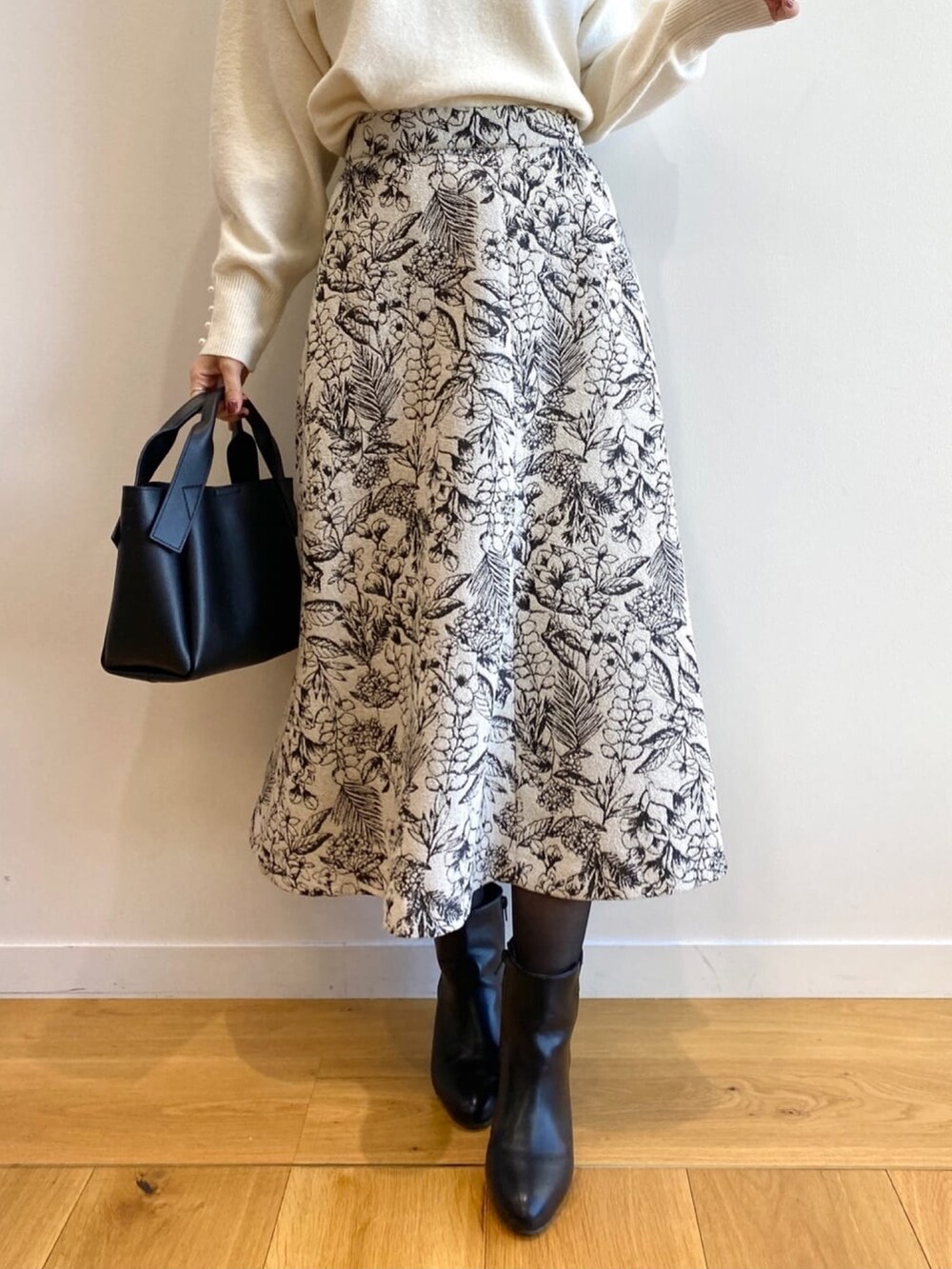 ホワイト系のニット/セーター、ブラック系のショルダーバッグ、ブラック系のブーツを着用したレディースの冬コーディネートの6枚目の写真