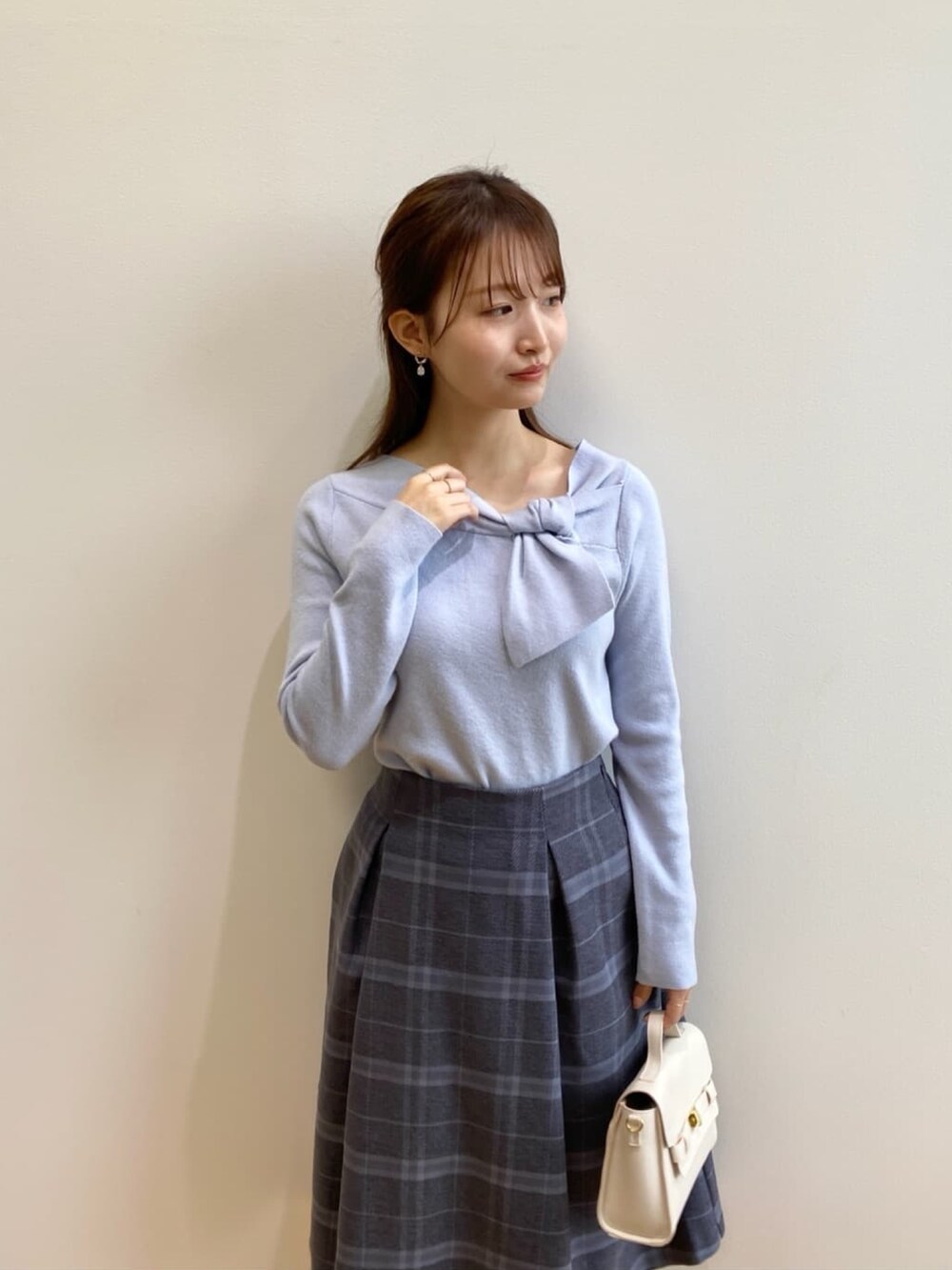 ブルー系のニット/セーター、グレー系のスカート、ホワイト系のショルダーバッグを着用したレディースの秋コーディネートの8枚目の写真