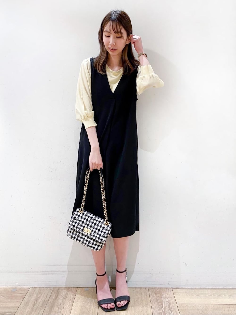 イエロー系のニット/セーター、ブラック系のサンダル、ブラック系のスカートを着用したレディースの春コーディネートの2枚目の写真