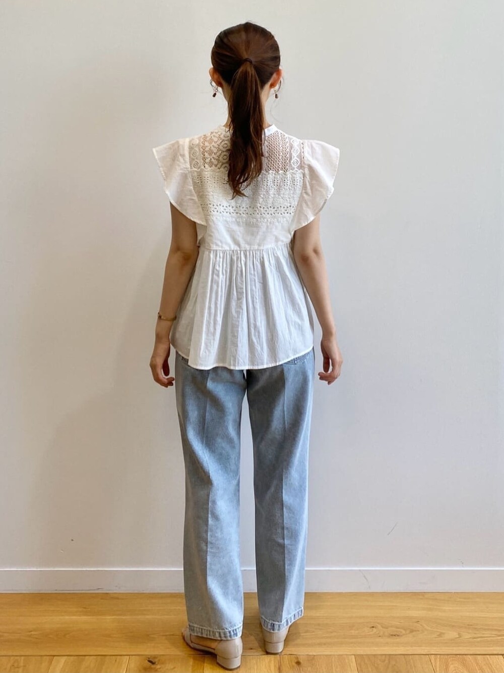 ブルー系のデニムパンツ、ベージュ系のサンダル、ホワイト系のシャツ/ブラウスを着用したレディースの夏コーディネートの4枚目の写真