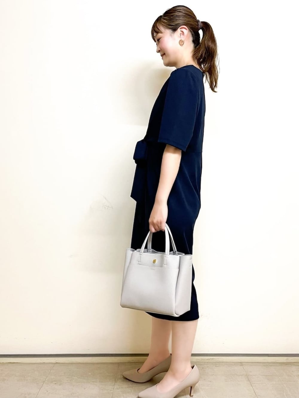 グレー系のトートバッグ、ブルー系のワンピース、ベージュ系のパンプスを着用したレディースの夏コーディネートの2枚目の写真