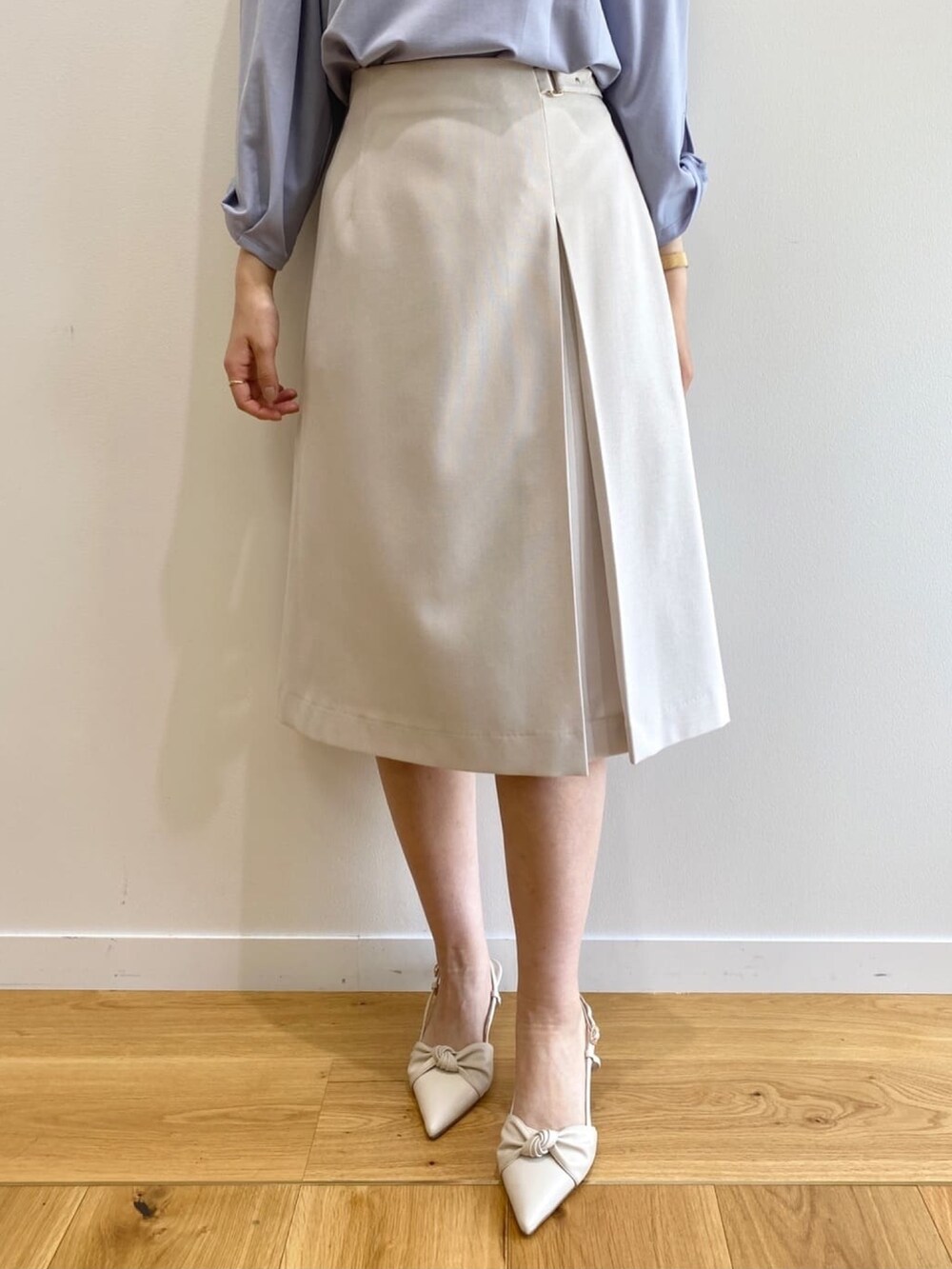 グレー系のスカート、ブルー系のTシャツ/カットソー、ホワイト系のパンプスを着用したレディースの春コーディネートの7枚目の写真