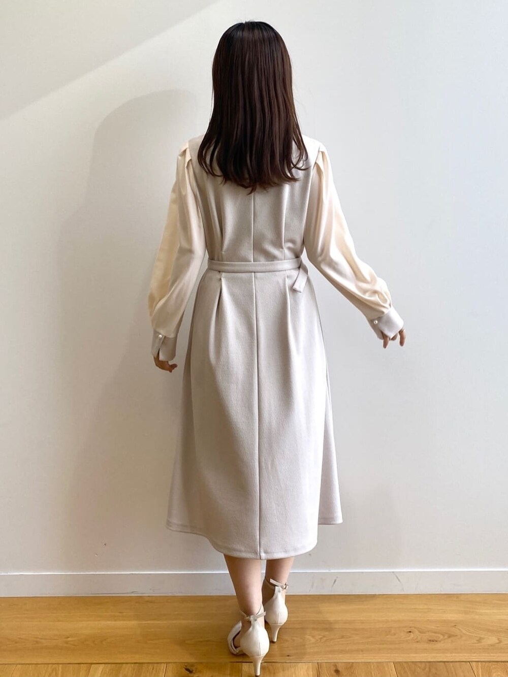 ベージュ系のワンピース、ホワイト系のパンプスを着用したレディースの冬コーディネートの3枚目の写真
