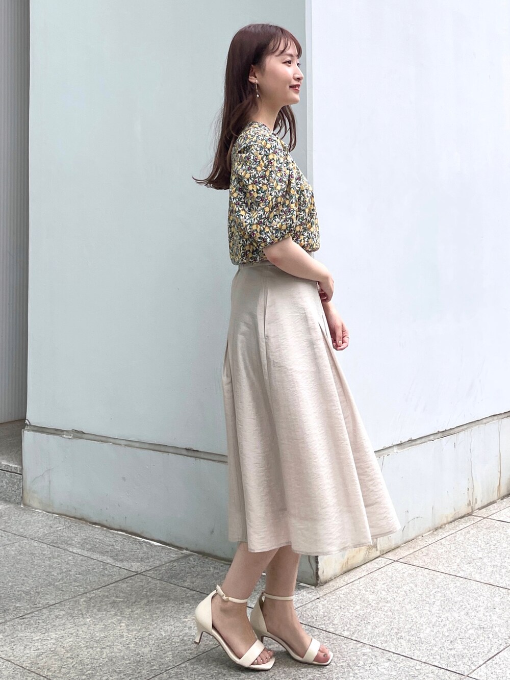 グレー系のスカート、ホワイト系のサンダル、ホワイト系のショルダーバッグを着用したレディースの夏コーディネートの2枚目の写真