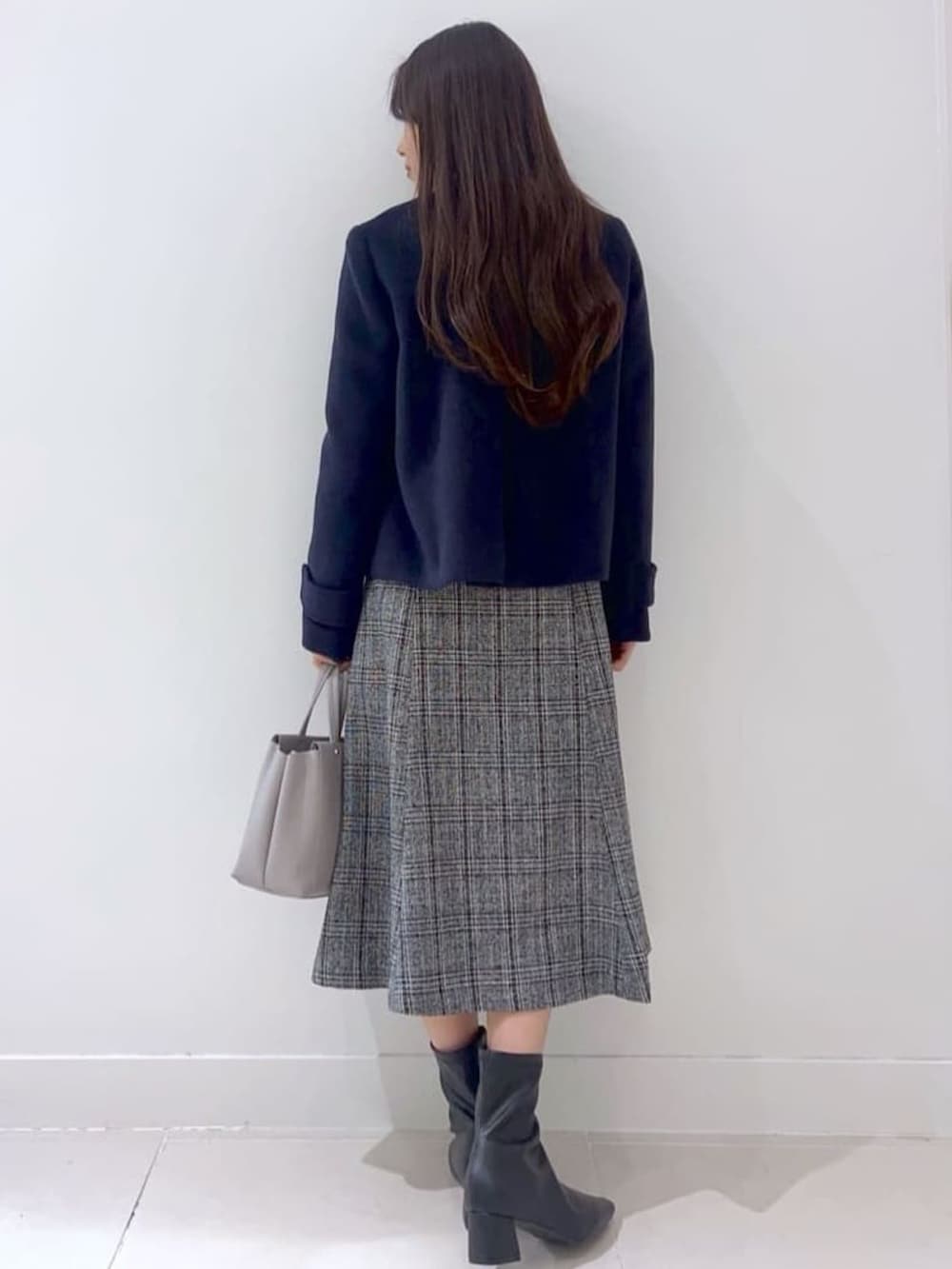 ブルー系のノーカラーコート、グレー系のニット/セーター、ブラック系のブーツを着用したレディースの秋コーディネートの3枚目の写真