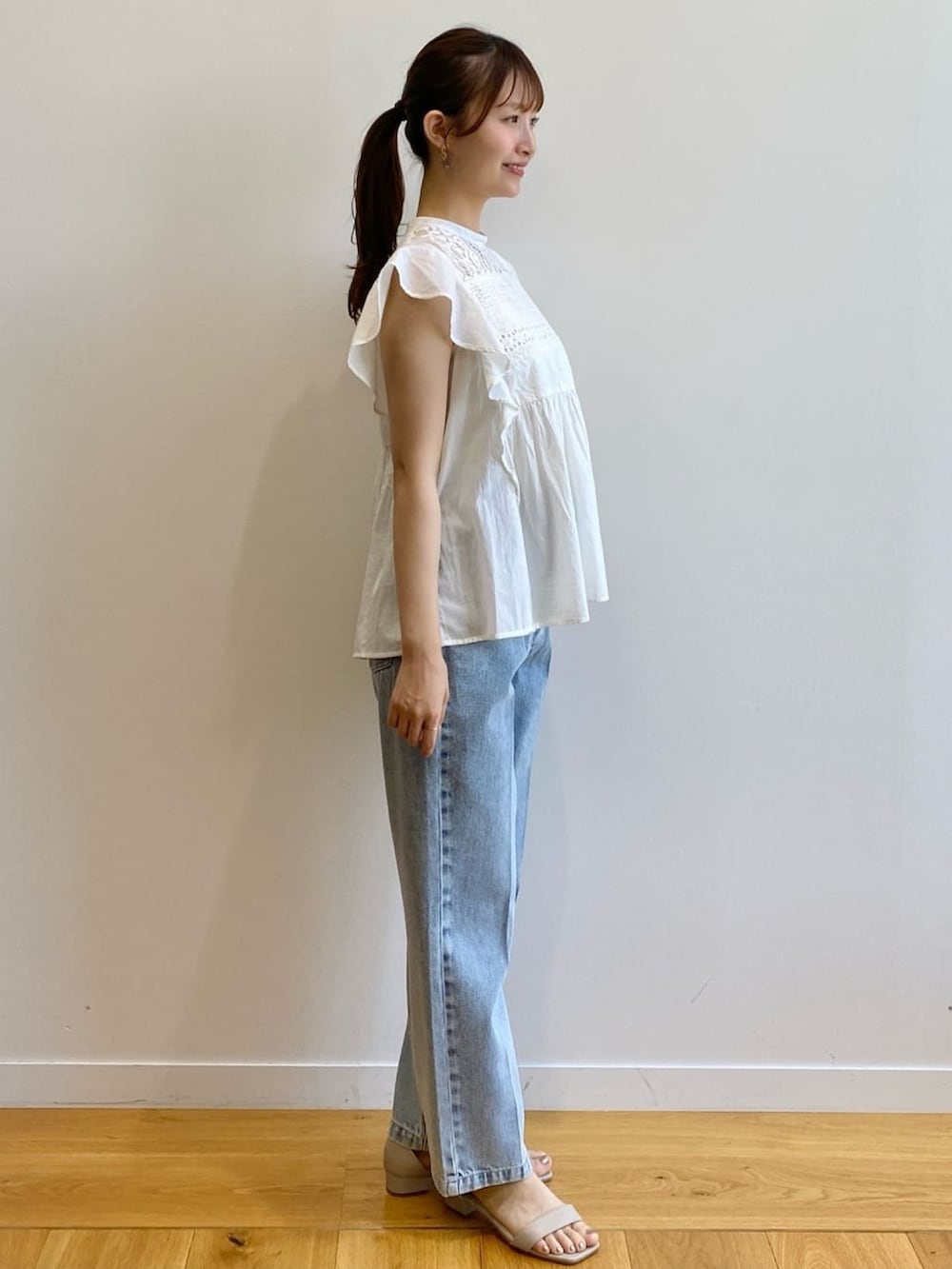 ブルー系のデニムパンツ、ベージュ系のサンダル、ホワイト系のシャツ/ブラウスを着用したレディースの夏コーディネートの3枚目の写真