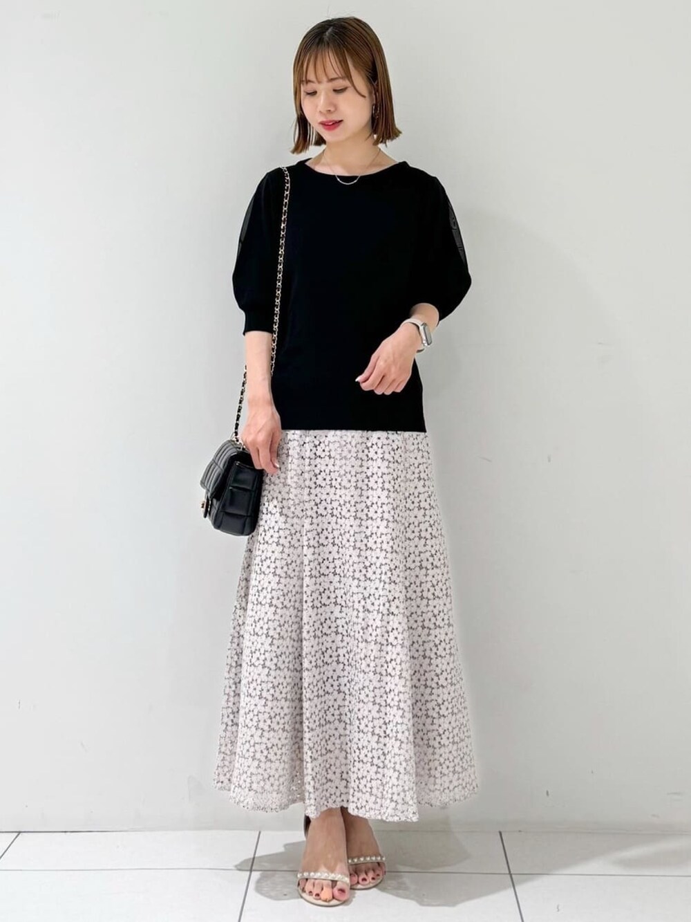 ブラック系のニット/セーター、ベージュ系のサンダル、ベージュ系のスカートを着用したレディースの夏コーディネートの4枚目の写真