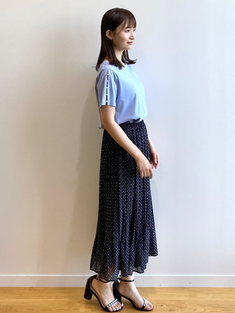 ブラック系のスカート、ブルー系のTシャツ/カットソー、ブラック系のサンダルを着用したレディースの夏コーディネートの2枚目の写真