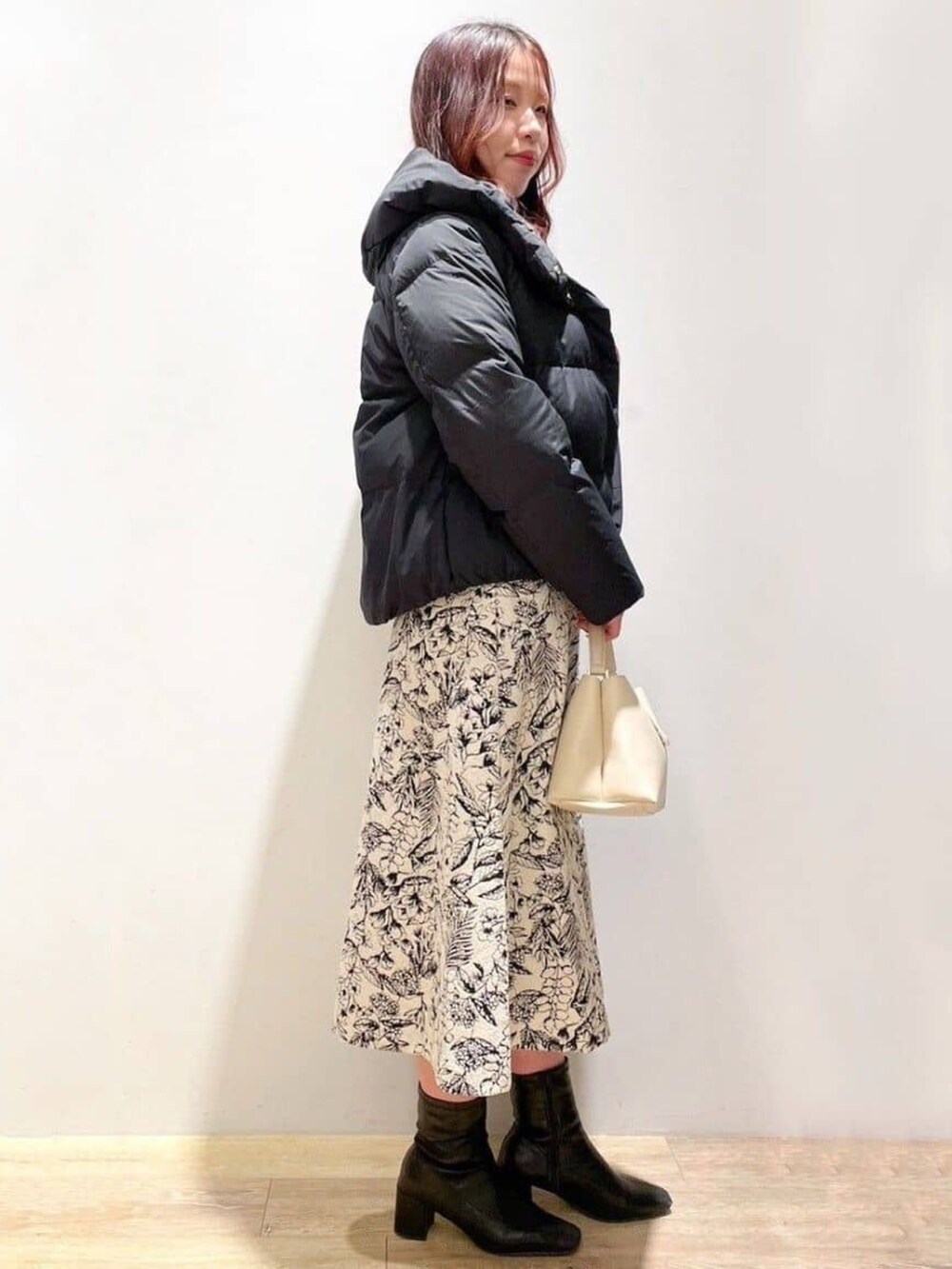 ベージュ系のスカート、ベージュ系のショルダーバッグ、ホワイト系のニット/セーターを着用したレディースの冬コーディネートの2枚目の写真