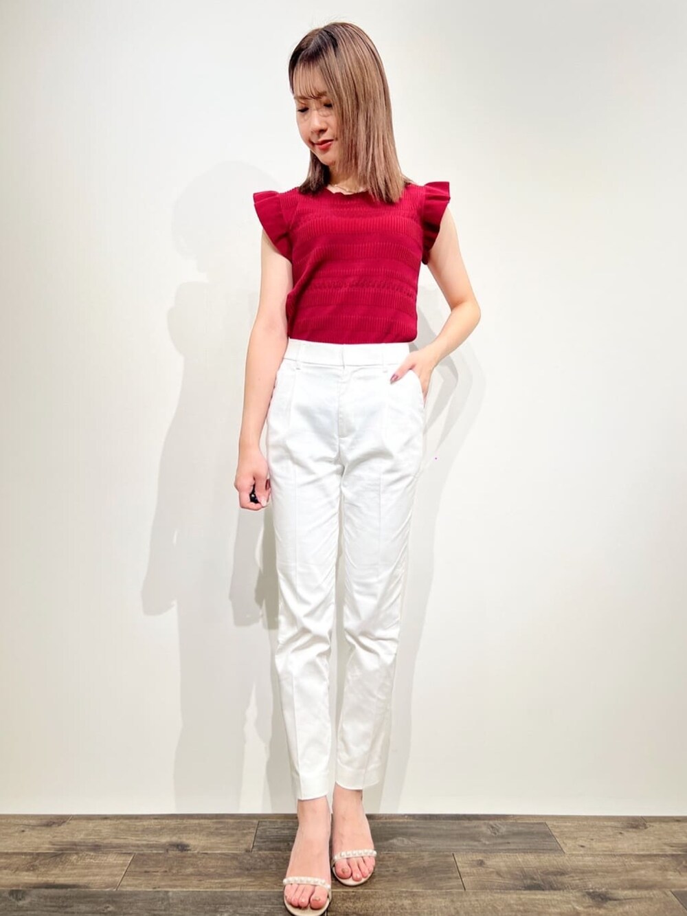 ホワイト系のその他パンツ、レッド系のニット/セーター、ベージュ系のサンダルを着用したレディースの春コーディネートの2枚目の写真