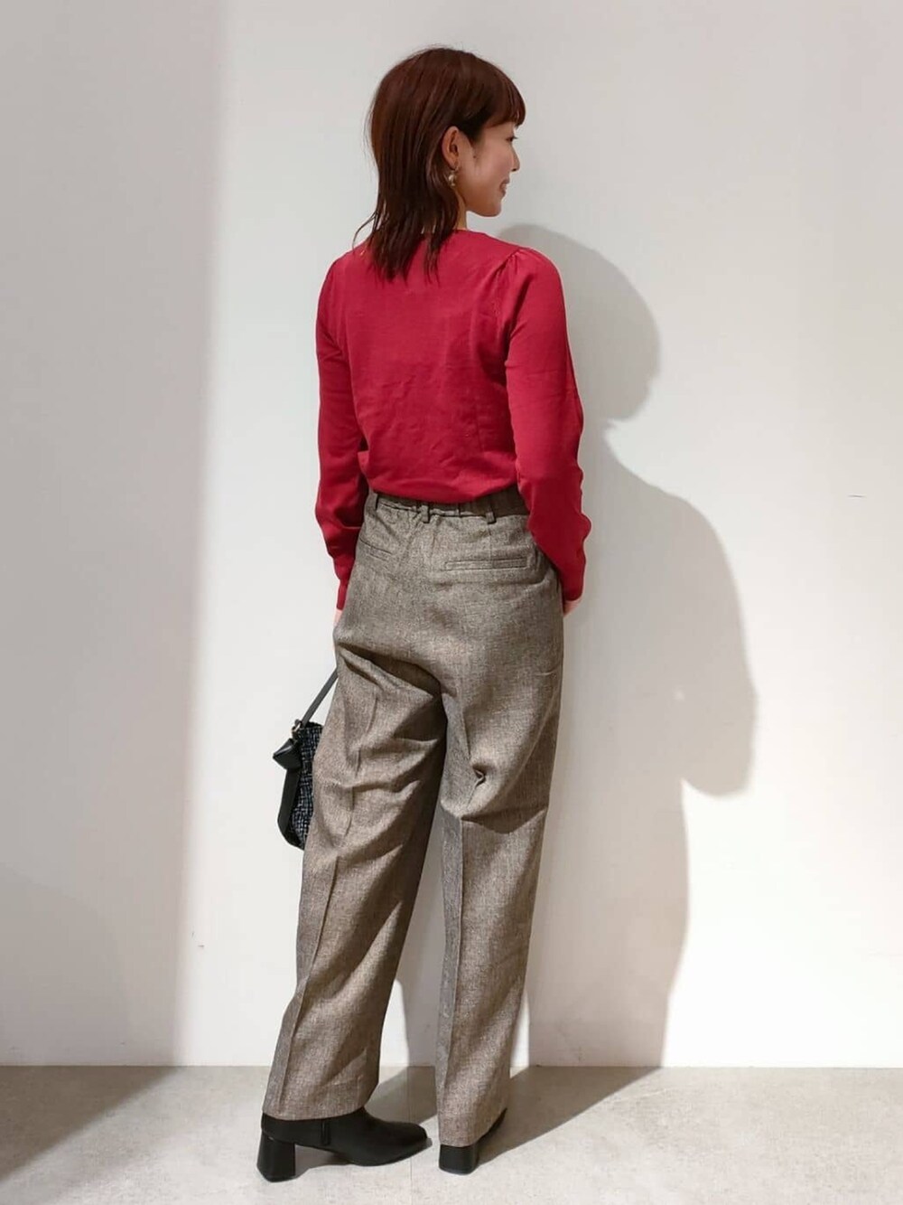 レッド系のニット/セーター、ブラウン系のその他パンツ、ブラック系のショルダーバッグを着用したレディースの秋コーディネートの5枚目の写真