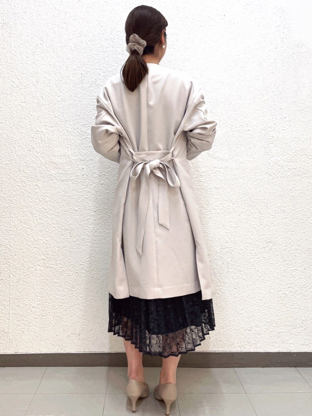 ブラック系のワンピース、ベージュ系のノーカラーコート、ベージュ系のパンプスを着用したレディースの春コーディネートの3枚目の写真