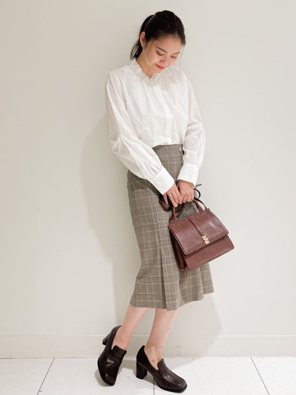 ホワイト系のシャツ/ブラウス、ベージュ系のスカート、ブラウン系のショルダーバッグを着用したレディースの秋コーディネートの2枚目の写真